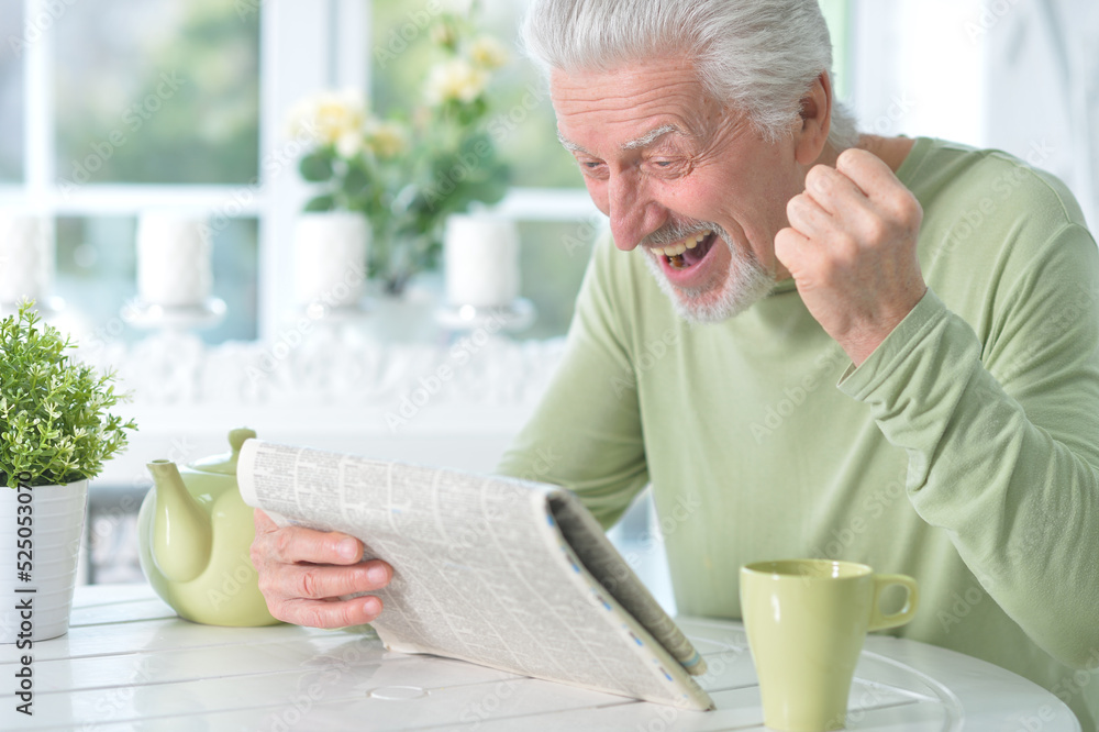 Emotional senior man reading newspaper Emotional senior man reading newspaper