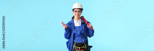 Female plumber with tools on light blue background