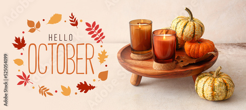 Text HELLO OCTOBER with beautiful aroma candles and pumpkins on light background
