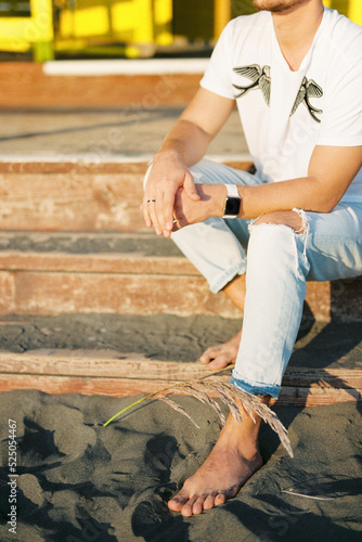 Young barefoot man sitting on the wooden steps