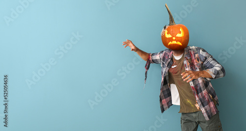 Scary man with carved pumpkin instead of his head on blue background with space for text. Halloween celebration