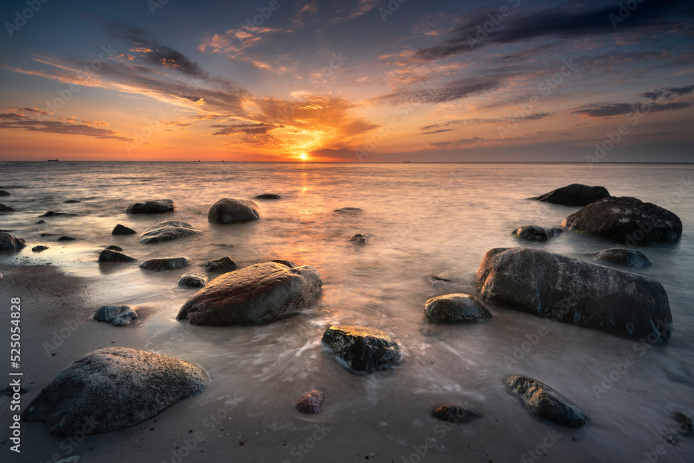 Obraz na płótnie Morze bałtyckie - wschód słońca na plaży z widokiem na fale i kamieniste wybrzeże bałtyku, koło klifu w Gdynia Orłowo w salonie