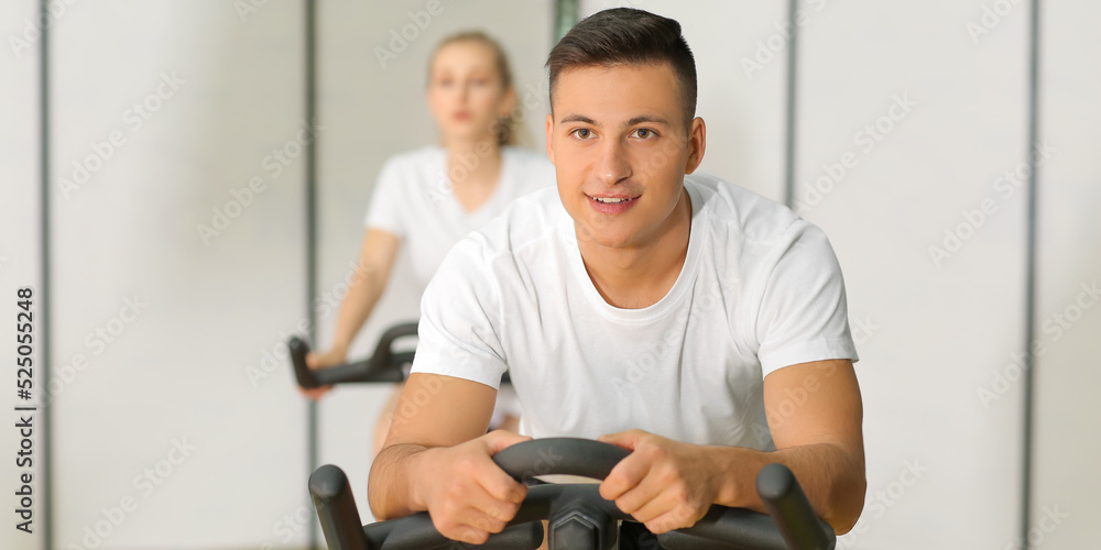 Young man training on exercise bike in gym Young man training on exercise bike in gym
