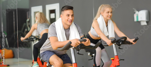Fototapeta Naklejka Na Ścianę i Meble -  Young people training on exercise bikes in gym