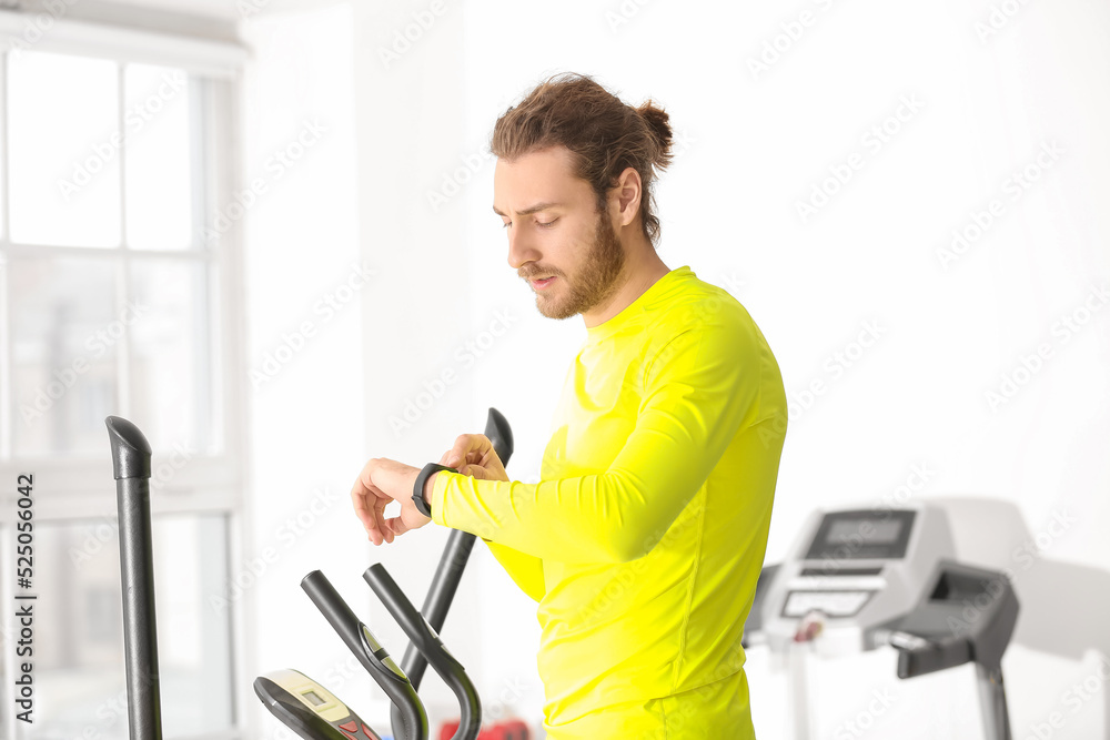 Sporty young man with fitness tracker training in gym Sporty young man with fitness tracker training in gym