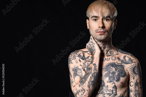 Young tattooed man on dark ...