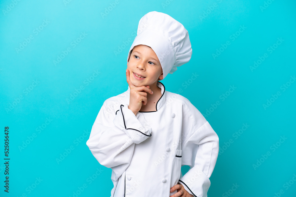 Little chef boy isolated on blue background thinking an idea while looking up Little chef boy isolated on blue background thinking an idea while looking up
