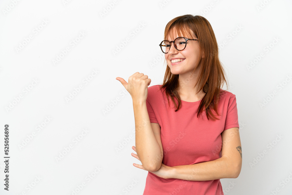 Redhead girl isolated on white background pointing to the side to present a product Redhead girl isolated on white background pointing to the side to present a product