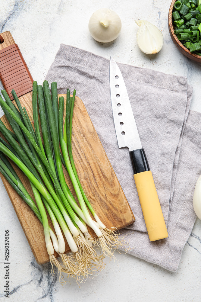 Wooden board with fresh green onion and knife on light background Wooden board with fresh green onion and knife on light background