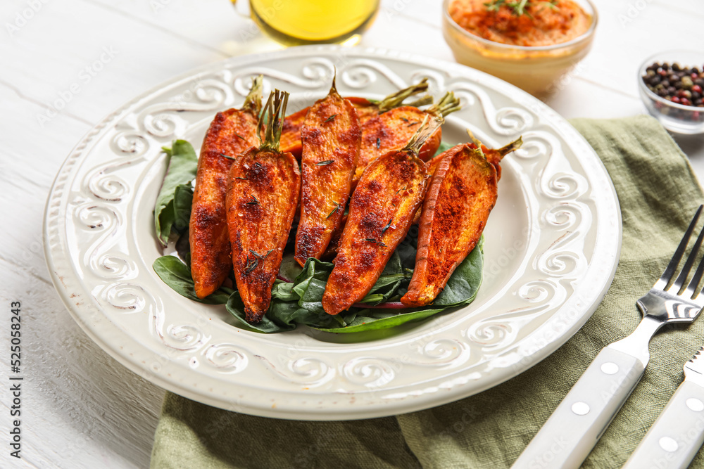 Plate with tasty baked carrots on light wooden table, closeup Plate with tasty baked carrots on light wooden table, closeup