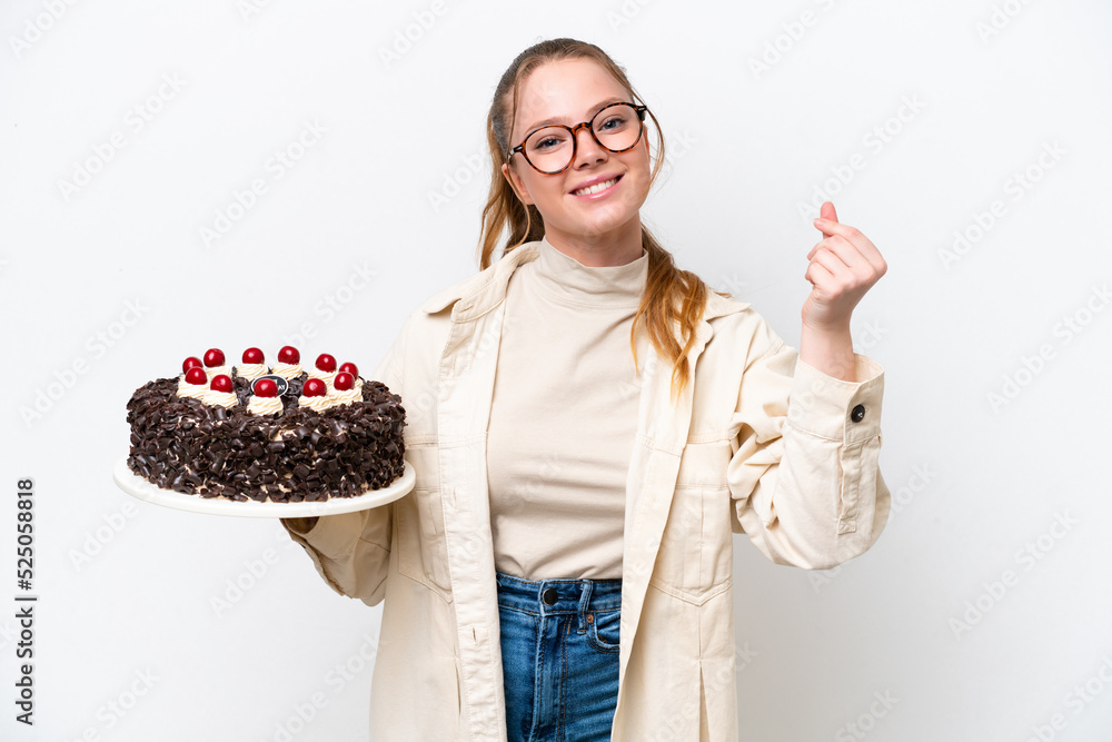 Young caucasian woman holding a Birthday cake isolated on white background making money gesture Young caucasian woman holding a Birthday cake isolated on white background making money gesture