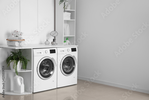 Interior of light laundry room with washing machines and shelving units