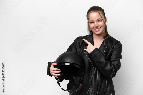 Young caucasian girl with a motorcycle helmet isolated on white background pointing to the side to present a product