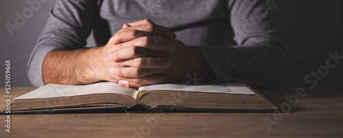 Hands of a man praying over a Bible © ARAMYAN