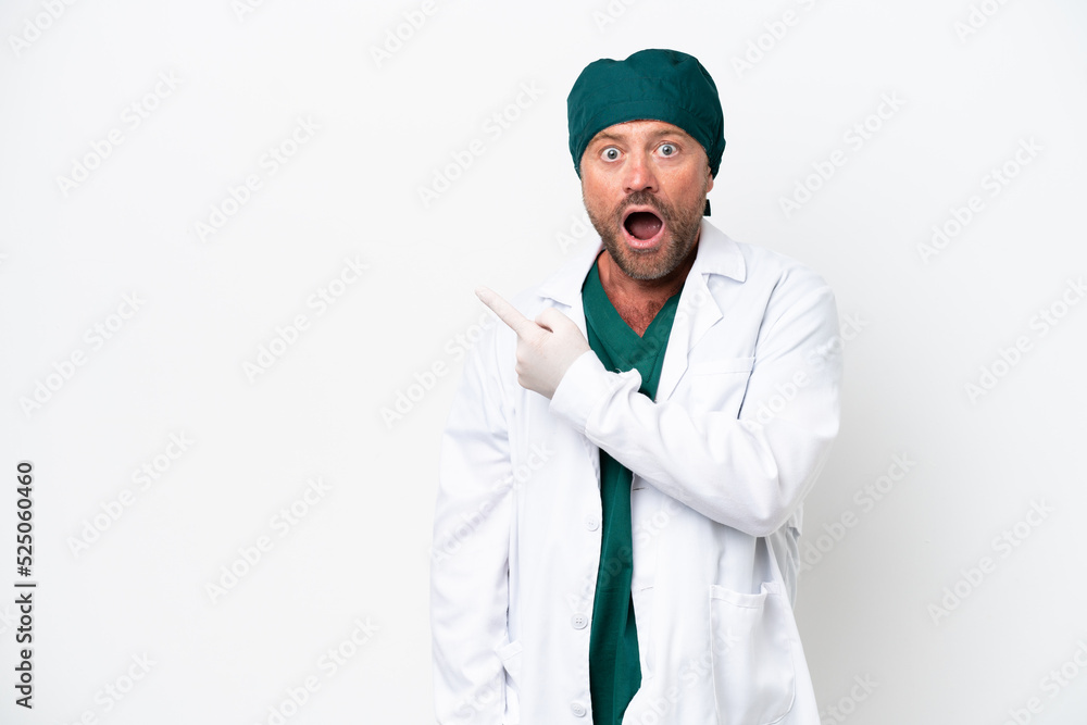 Middle age surgeon in green uniform isolated on white background surprised and pointing side Middle age surgeon in green uniform isolated on white background surprised and pointing side