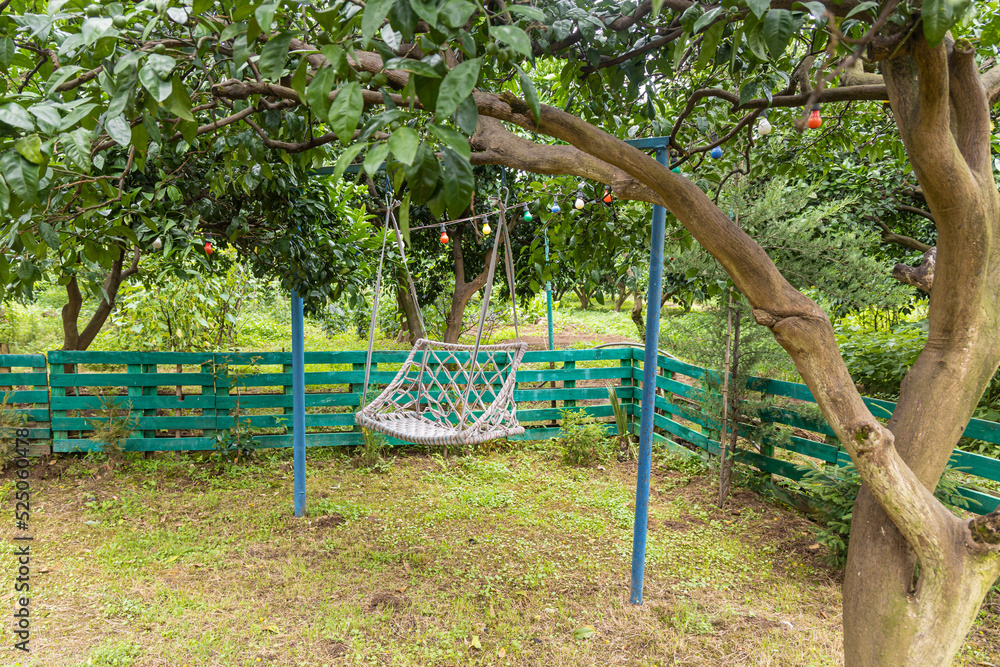 There is a white wicker swing on a children's playground in the courtyard in summer There is a white wicker swing on a children's playground in the courtyard in summer