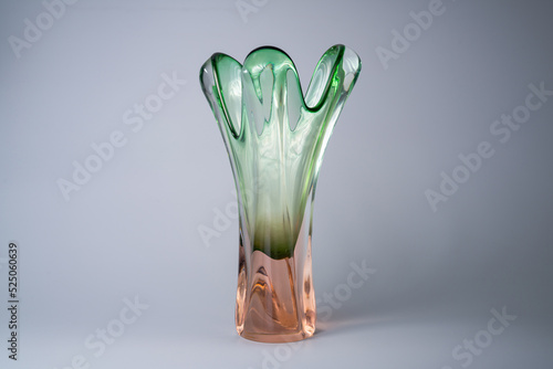 Bohemian glass long vase on grey background in the studio. Transparent crystal pink green vase. Waterglass for flowers. Glass bowl for home decor. Glassware handmade. photo