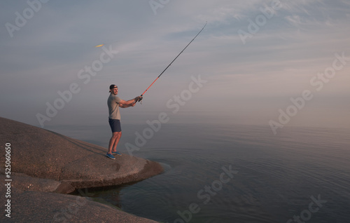 A fisherman on the coast with a fishing rod casts the bait into the water