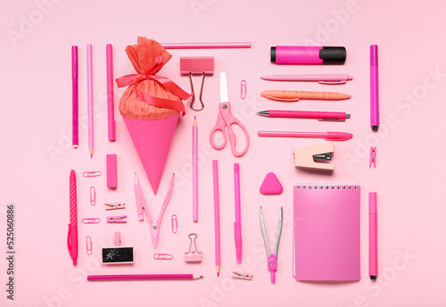 School cone with stationery supplies on pink background