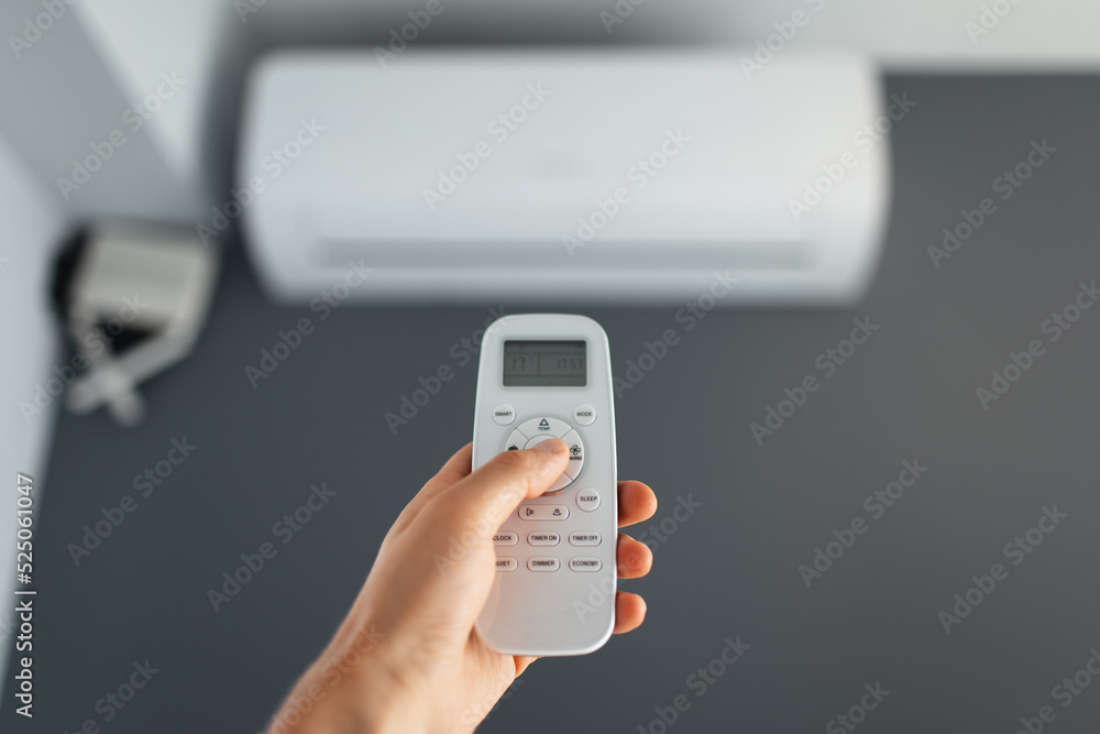 Close-up of male hand using remote control of the air conditioner. Close-up of male hand using remote control of the air conditioner.
