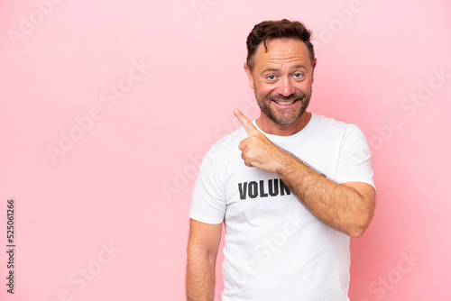 Middle age volunteer man isolated on pink background isolated on pink background pointing to the side to present a product