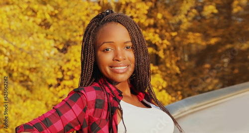 Portrait of young smiling african woman with dreadlocks in autumn park photo