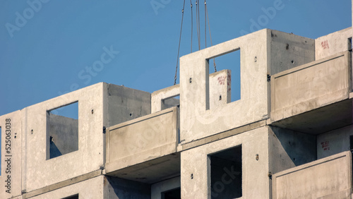 Crane plants the wall on the high-rise building. Blue sky background. photo