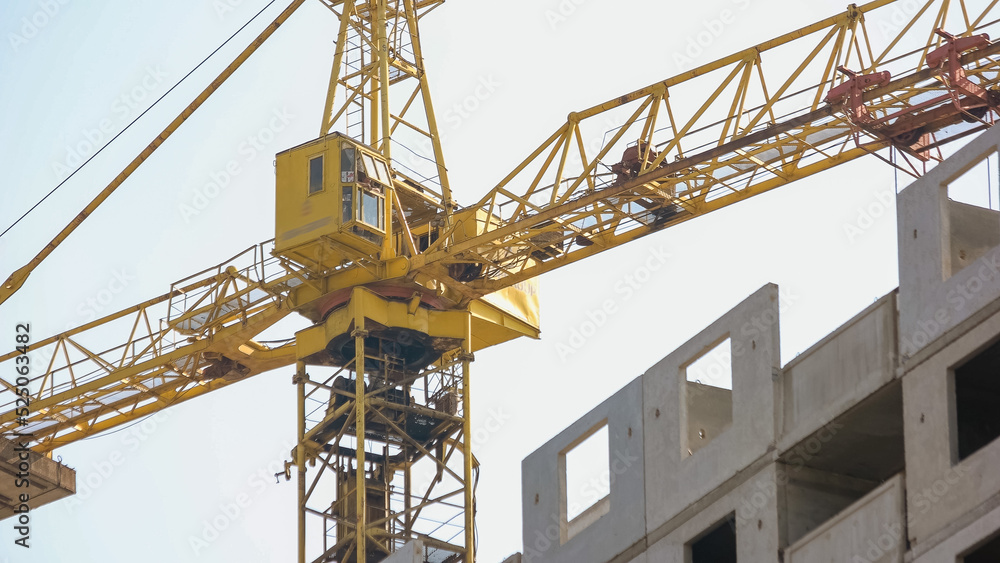 Yellow crane on the background of building. White sky background.