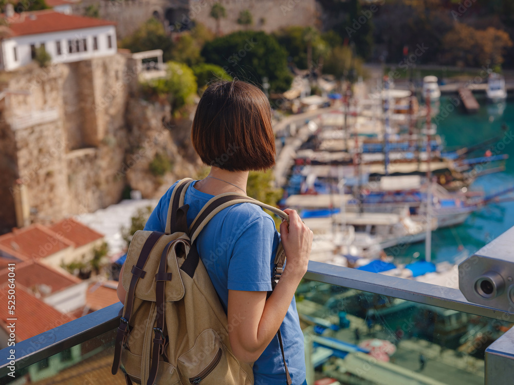 Obraz premium travel to Turkey, old town Antalya Kaleci. Happy asian female tourist traveller with backpack walks in old city. Woman on lookout over the old town and the port from viewpoint