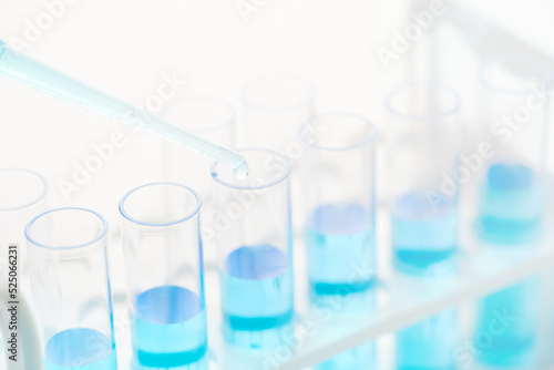 concept of science biology Pipette dropping a sample into a test tube with blue liquid on white background 