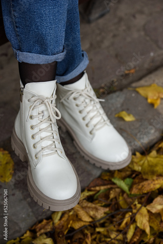 Female legs in a jeans and white fashion boots with laces.
