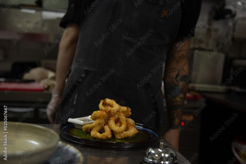 chef prepares deep-fried onion rings in the restaurant kitchen.