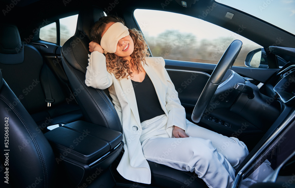 Charming woman in sleeping mask sitting on driver seat and smiling