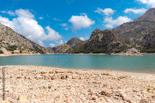 gor blau reservoir with large water capacity located between the mountains of mallorca with a cloudy sky.