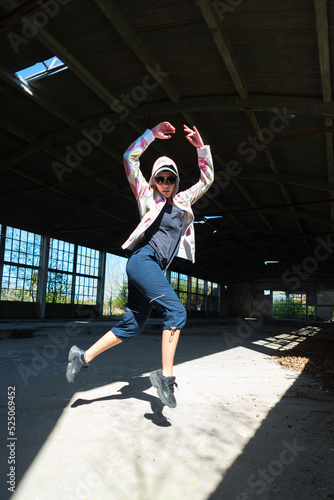 Young female hip hop dancer dancing and jumping in abandoned building on a sunny summer day 