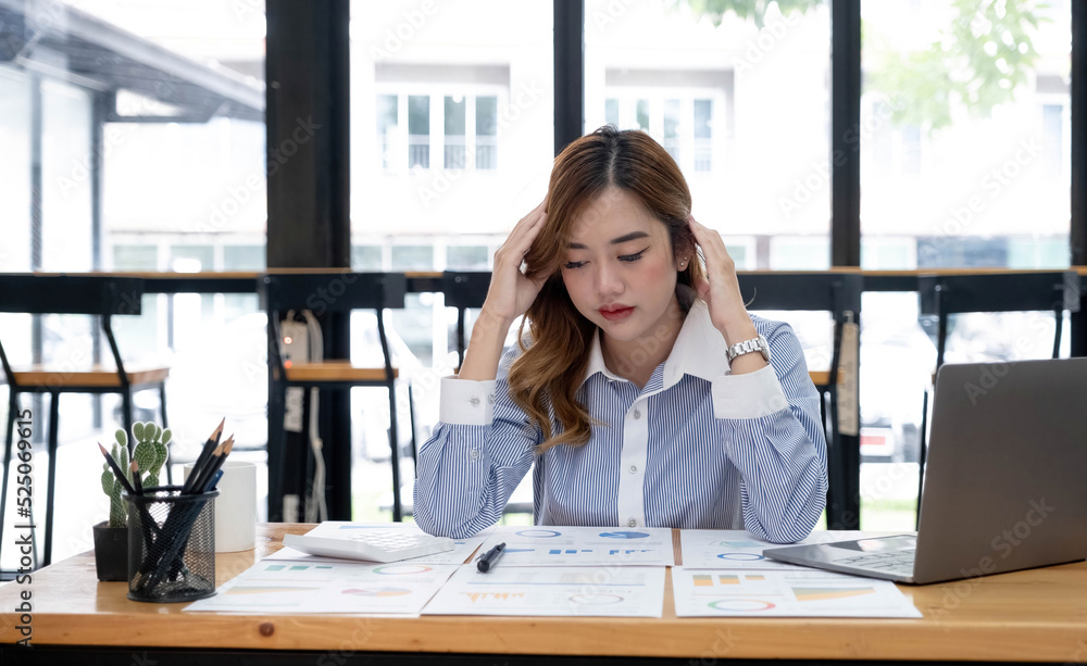 Young Asian businesswoman working on a tablet, is stressed has a headache and thinks hard at the office. Young Asian businesswoman working on a tablet, is stressed has a headache and thinks hard at the office.