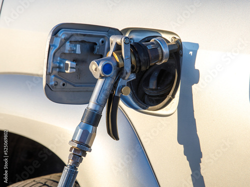 Close-up detail view of fuel autogas pump gun connected with noozle adapter to car tank to refill at car gas filling station. Refueling vehicle with liquefied lpg or lng product. Safety technology photo