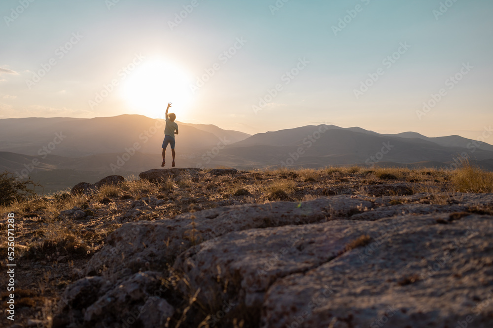 silhouette of a jumping man against the background of the sky and sunset in the mountains