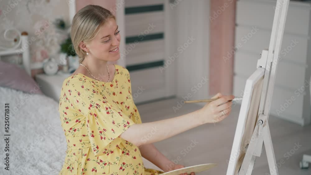 Pregnant woman painting a picture at home Pregnant woman painting a picture at home