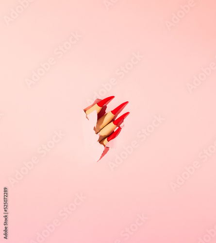 Photo Halloween creative layout made of witch's hand with red nails against pastel pink background