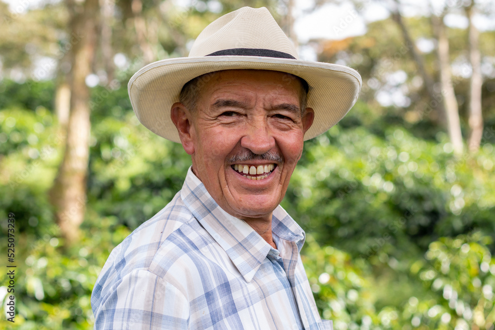 Portrait of an old Colombian peasant man wearing a hat and looking at the camera with a big smile.