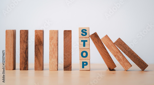 Fotografie Stop wording print on wooden block cube protect wooden falling domino for risk management concept