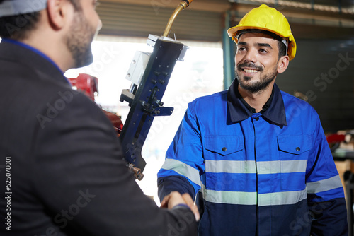 factory worker or engineer shaking hands with businessman and making deal with work in the factory