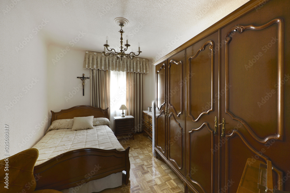 Bedroom with single bed with matching dark wood headboard with large wardrobe and light oak parquet flooring