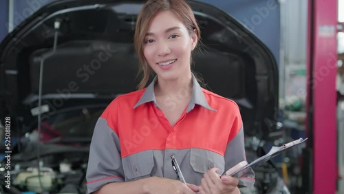 Portrait of Beautiful Asian young female mechanic in uniform with smile. Professional inspects check engine in Auto garage. Auto repair service and maintenance Concept.