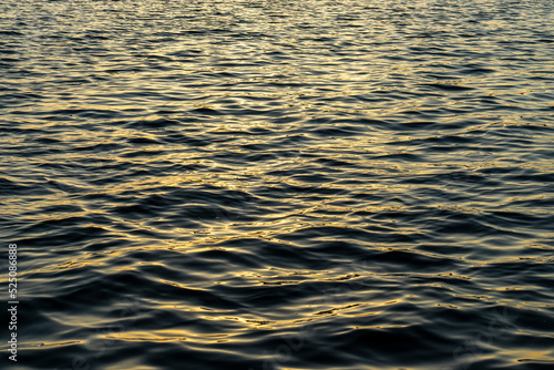 Rippled water surface of Aegean sea by sunset. Abstract, background, texture. Selective focus, noise effect and grainy texture. 