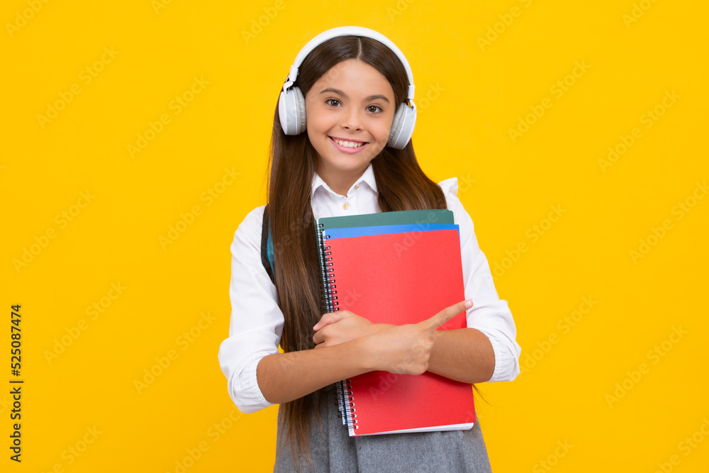 Teenage student, school girl with books and headphones listening to music on yellow background. Happy schoolgirl. Teenage student, school girl with books and headphones listening to music on yellow background. Happy schoolgirl.