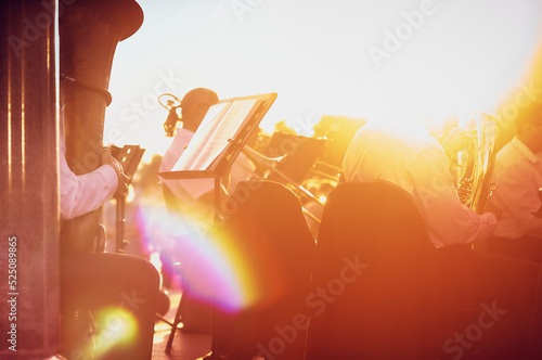 People playing wind musical instruments at sunset, creative abstract blur background with bokeh effect. Orange light.