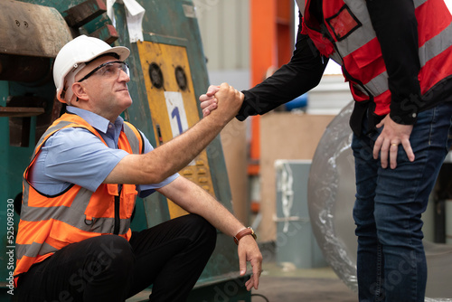 Photos factory worker hands helping his friend to get up after a break in the factory