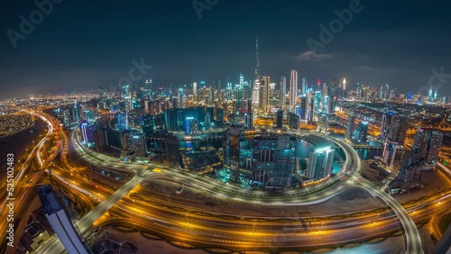 Panoramic skyline of Dubai with business bay and downtown district day to night timelapse. Aerial wide angle view of many modern skyscrapers with traffic on al khail road after sunset. photo